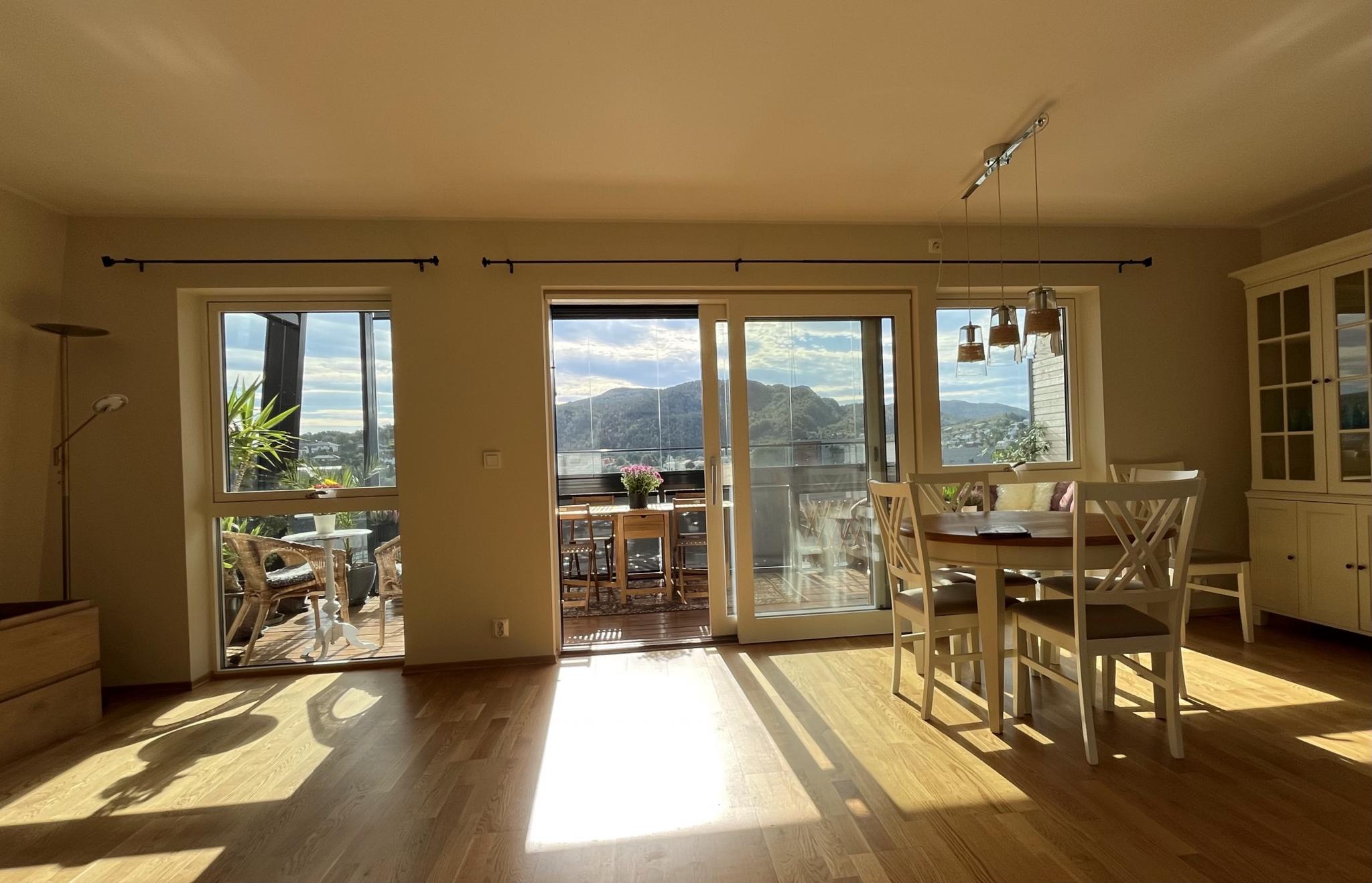 Stuen med store vinduer og skyvedør til den innglassede balkongen.